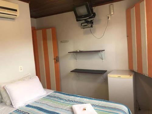 a bedroom with a bed and a tv on the wall at HOSTEL DA LU e HOSPEDAGEM FATIMA in Pirenópolis