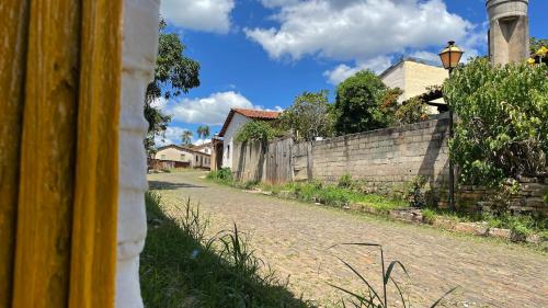 a brick road with a fence and a wall at HOSTEL DA LU e HOSPEDAGEM FATIMA in Pirenópolis