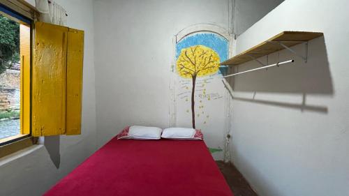 a room with a bed with a tree on the wall at HOSTEL DA LU e HOSPEDAGEM FATIMA in Pirenópolis