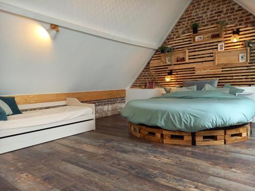 a bedroom with a bed and a bench and a brick wall at A l'Ombre du Laurier in Monchy-au-Bois