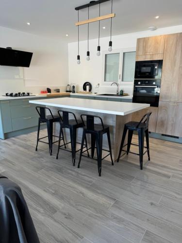 una cocina con una gran mesa blanca y sillas negras en Karzen, en Ghisonaccia