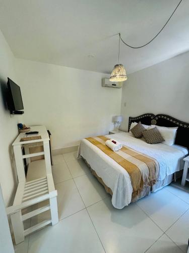 a bedroom with a bed and a television and a table at Pousada Coisa e Tao in Arraial d'Ajuda