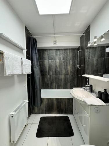 une salle de bain avec un lavabo et une baignoire dans l'établissement Confort et charme aux Arcades, à Montigny-le-Bretonneux