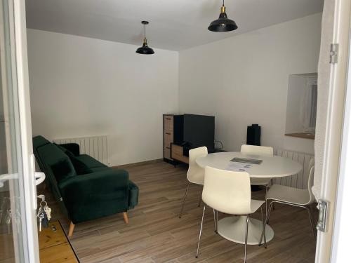 - un salon avec une table et un canapé vert dans l'établissement Appartement St Amant Tallende 2 adultes 1 enfant possible, à Saint-Amant-Tallende