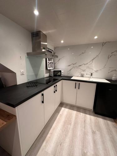 une cuisine avec des armoires blanches et un comptoir noir dans l'établissement Jolie dépendance équipée, à Cholet