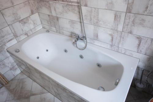 a white bath tub in a tiled bathroom at Къща за гости ANGELOVI in Veliko Tŭrnovo