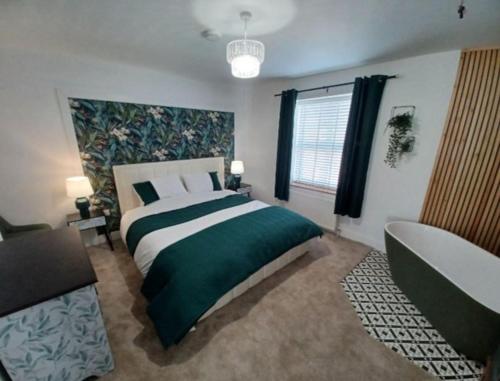 a bedroom with a green and white bed and a tub at 8 Guests Large cottage Hotub in Hornsea