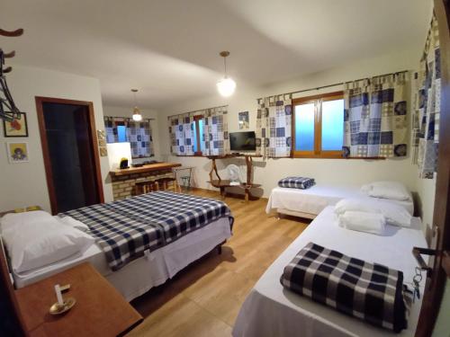 a hotel room with two beds and a desk at Hospedagem Maria de Liu in Palmeiras