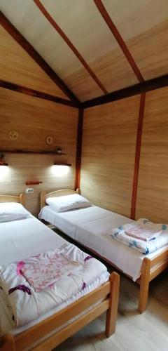 two beds in a room with wooden walls at Kucerak na Drini in Bajina Bašta