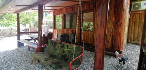 a porch of a wooden cabin with a swing at Kucerak na Drini in Bajina Bašta