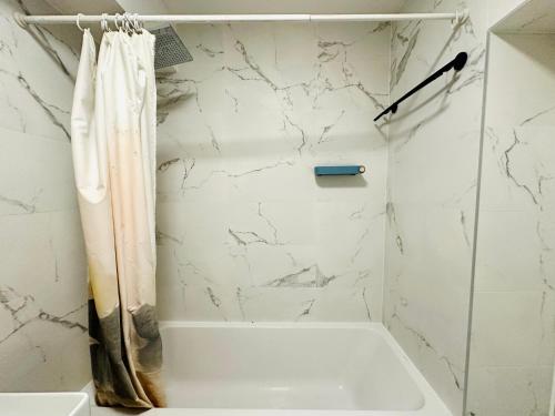 La salle de bains blanche est pourvue d'une baignoire et d'un rideau de douche. dans l'établissement Dream Dwell Paris-Deluxe Studio 650m near Arc de Triomphe, à Paris