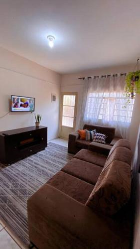a living room with a couch and a tv at Casa térrea - Centro Guararema in Guararema