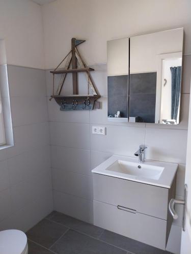 a white bathroom with a sink and a mirror at Ferienwohnung Schnelzer in Sahlenburg
