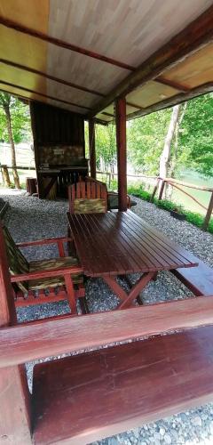 a picnic table and two chairs sitting under a roof at Kucerak na Drini in Bajina Bašta