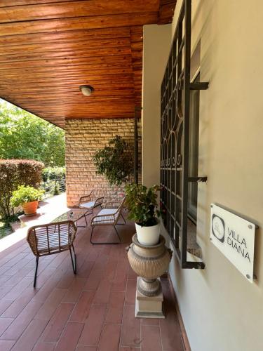 a patio with chairs and a porch with a wooden ceiling at Villa Diana in Montecatini Terme