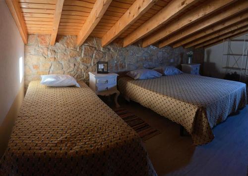 a bedroom with two beds and a stone wall at Casa Emília & Alda in Juncal