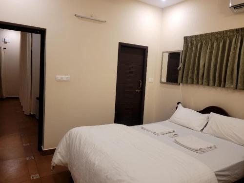 a bedroom with a white bed and a black door at Ponni Homestay Kumbakonam in Kumbakonam