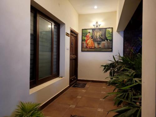a hallway with plants and a painting on the wall at Ponni Homestay Kumbakonam in Kumbakonam