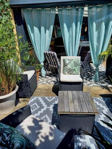 a patio with a bench and a table and chairs at L'appart des mésanges in LʼHerbergement