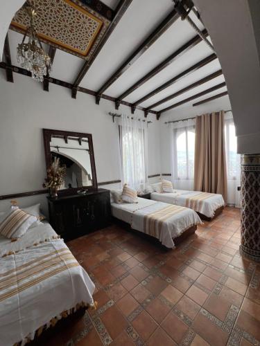 a room with three beds and a mirror at Dar Al Hurra Appartement Andalou Chaouen in Chefchaouen
