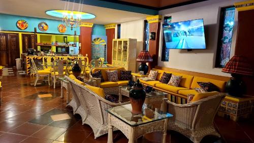 a restaurant with yellow couches and tables and chairs at Casa Virgilio B&B in Nuevo Vallarta 