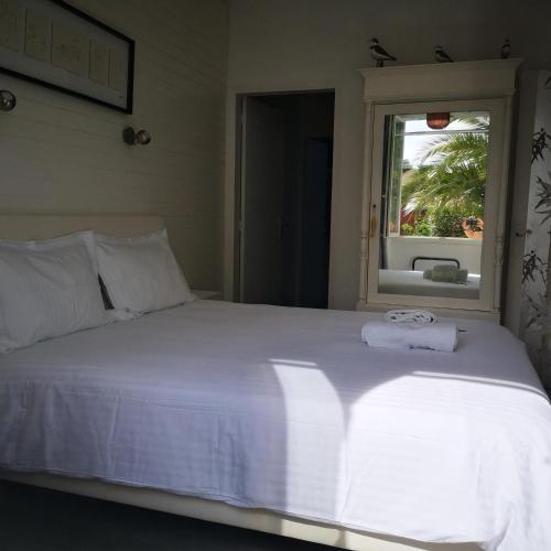 une chambre avec un lit blanc avec une fenêtre dans l'établissement Le chat bleu suite parentale chez l habitant cuisine partagée, à Beauvoir-sur-Mer