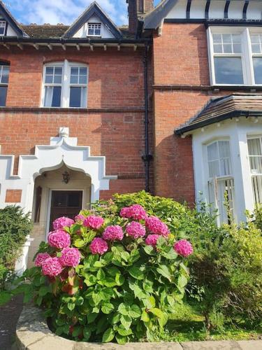 a brick house with pink flowers in front of it at Spaside Apartment in Scarborough