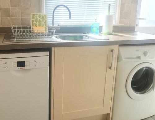 a kitchen with a sink and a washing machine at Spaside Apartment in Scarborough