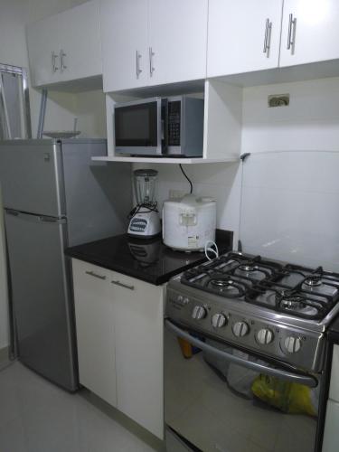 a kitchen with a stove and a microwave at Apartamento en Centro Historico de Lima in Lima