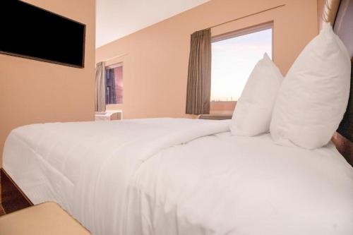 a bedroom with a bed with white sheets and a window at Royal Inn & Suites in Adairsville