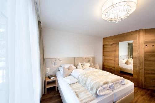 a bedroom with a large white bed with a chandelier at Superior Hotel Post Ischgl in Ischgl