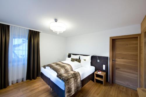 a bedroom with a bed with white sheets and pillows at Superior Hotel Post Ischgl in Ischgl