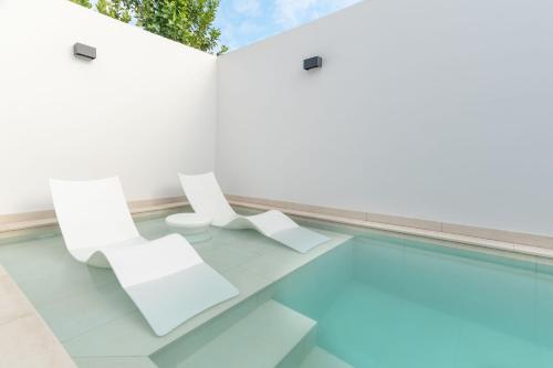 2 sillas blancas y una piscina en Bungalow SIENA Center Playa del Inglés, en Maspalomas