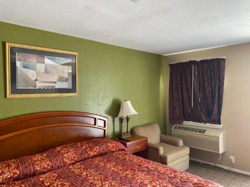 una habitación de hotel con una cama y una silla en American Star Inn, en Baird