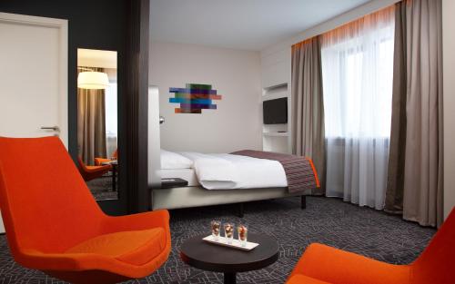 Habitación de hotel con 1 cama y 2 sillas de color naranja en Demidov Plaza, en Nizhni Taguil