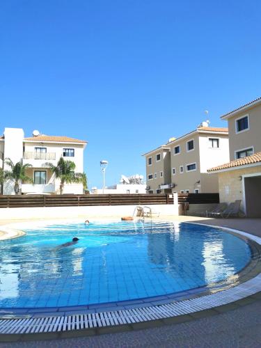a person swimming in a swimming pool with buildings in the background at Holiday apartment in Kyklades Complex with gym&pool in Paralimni