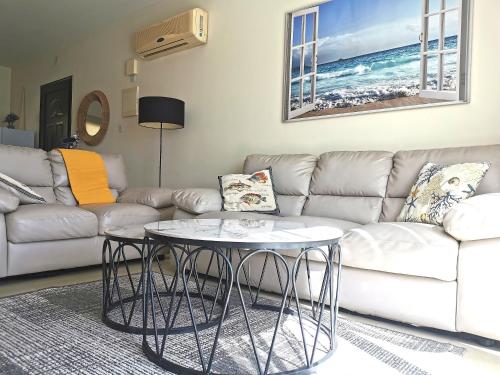 a living room with a couch and two tables at Holiday apartment in Kyklades Complex with gym&pool in Paralimni