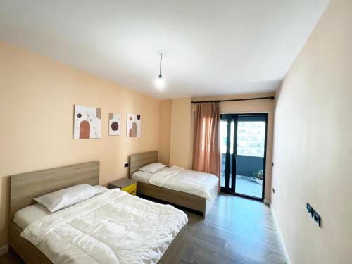 a bedroom with two beds and a door to a balcony at B2 Apartment in Tirana