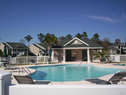 ein großer Swimmingpool mit Stühlen und einem Haus in der Unterkunft Pawleys Island Retreat! in True Blue