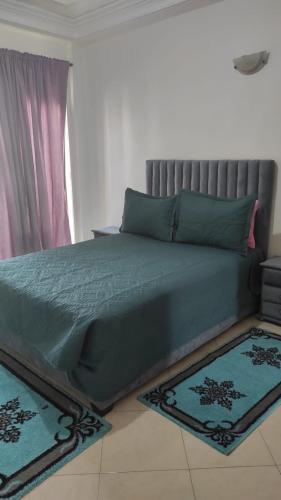 a bedroom with a bed with blue sheets and rugs at Les Appartements de la Place Atlas in Fès