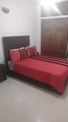 a red bed with red sheets in a room at Les Appartements de la Place Atlas in Fès