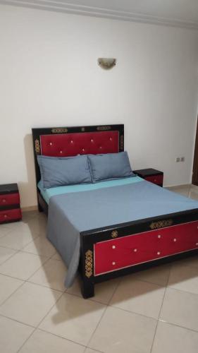 a bed with a red headboard in a room at Les Appartements de la Place Atlas in Fès