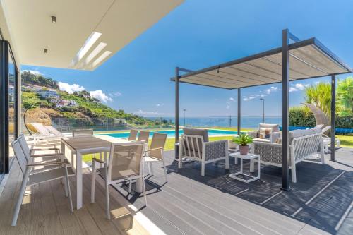 a deck with a table and chairs and a view of the ocean at Luxury Diamond House by Holiday Rental Madeira in Funchal