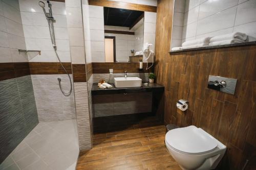 a bathroom with a toilet and a sink and a shower at Хотел Панорама in Pleven