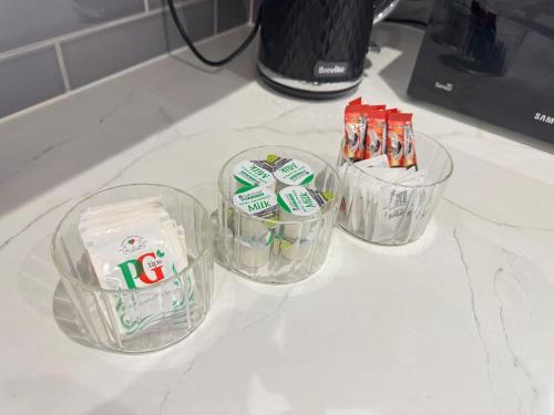 four plastic containers of toothbrushes and toothpaste on a counter at Modern 3 Bedroom Home - Free Driveway Parking - 6 Guests - Upstairs Bathroom and Downstairs WC in Armthorpe