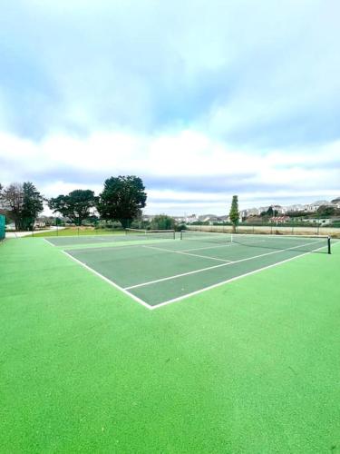 a tennis court with green grass on it at The Lobster Pot in Tywardreath