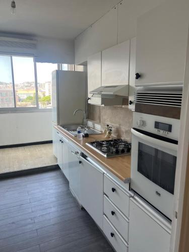 une cuisine avec des armoires blanches et un four à plaques de cuisson dans l'établissement Appartement 2 chambre et grand séjour 100m2 a 5 min du stade VELODROME, à Marseille