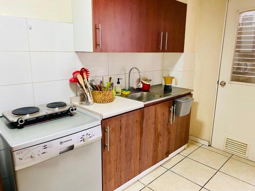 a small kitchen with a sink and a stove at Departamento Central, con estacionamiento gratuito in Talca