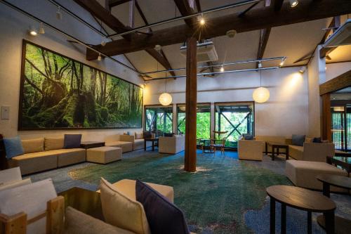 a lobby with couches and tables and a large painting on the wall at Jomon no Yado Manten in Yakushima
