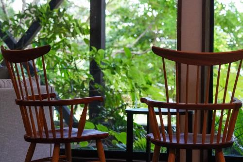 two wooden chairs sitting in front of a window at Jomon no Yado Manten in Yakushima